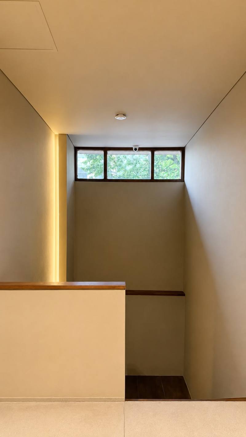 Escalera interior con ventana horizontal hacia los árboles