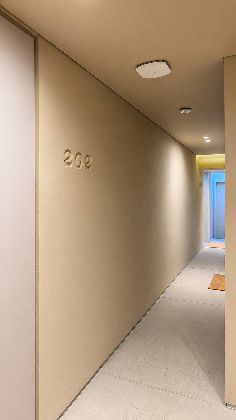 Corredor interior con la numeración 202 en muro de microcemento